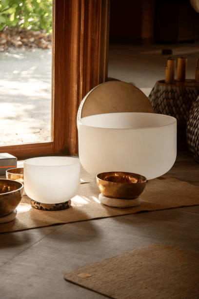 Bronze and crystal singing bowls set up in a wooden yoga and wellness retreat room.