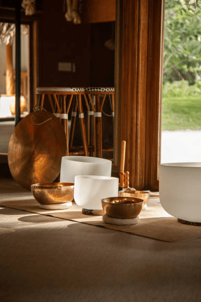 Crystal singing bowls and bronze sound bowls arranged in a sunlit meditation room.
