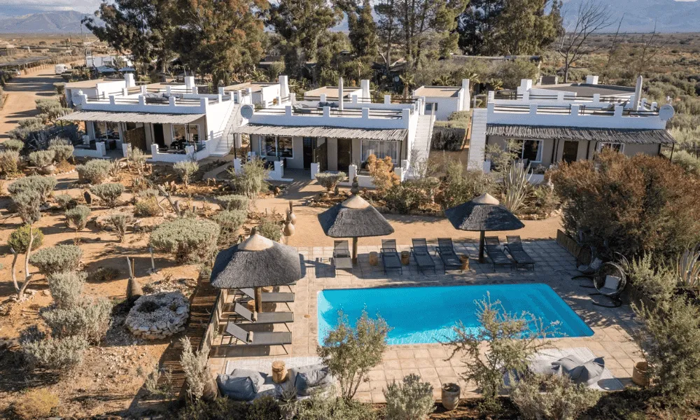 Aerial view of Inverdoorn Private Game Reserve’s whitewashed chalets, desert garden and turquoise swimming pool in the Little Karoo.