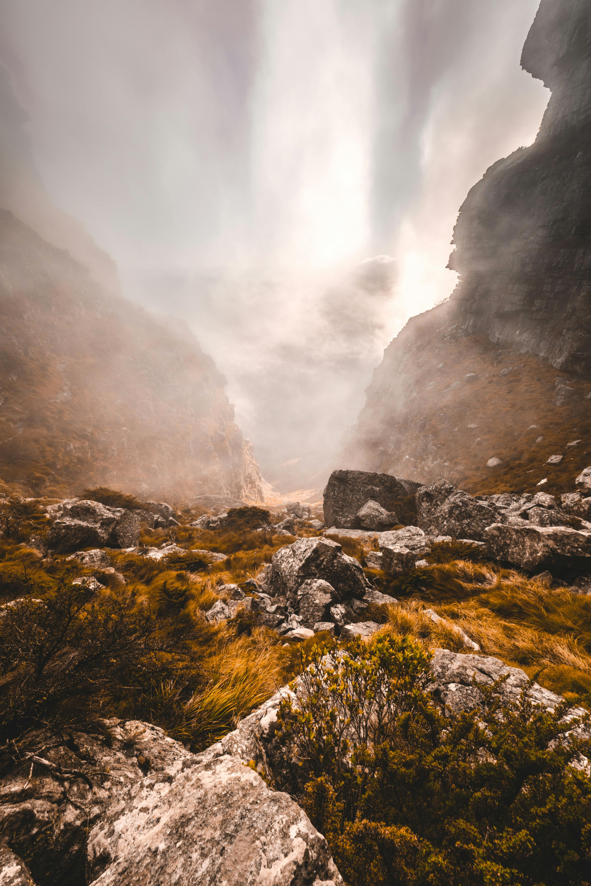 Sunlight streaming through a misty Table Mountain canyon with dramatic rock formations.