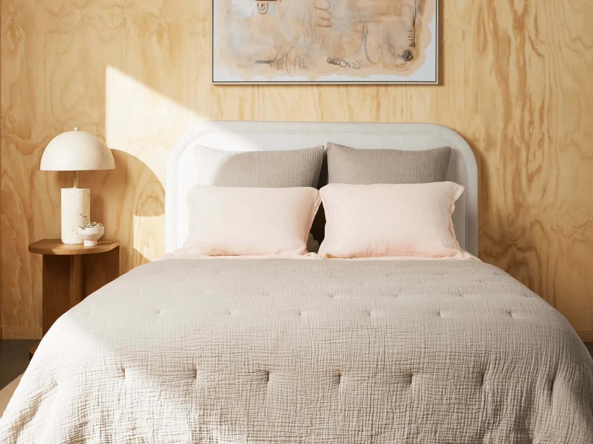 Sunlit minimalist bedroom with a soft white headboard.