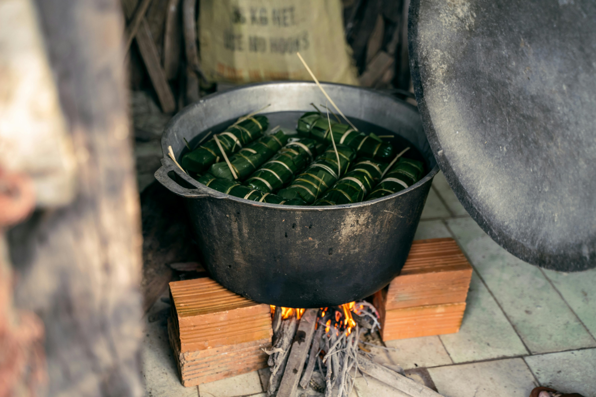 Vietnamese banana leaf parcels steaming in a large pot.