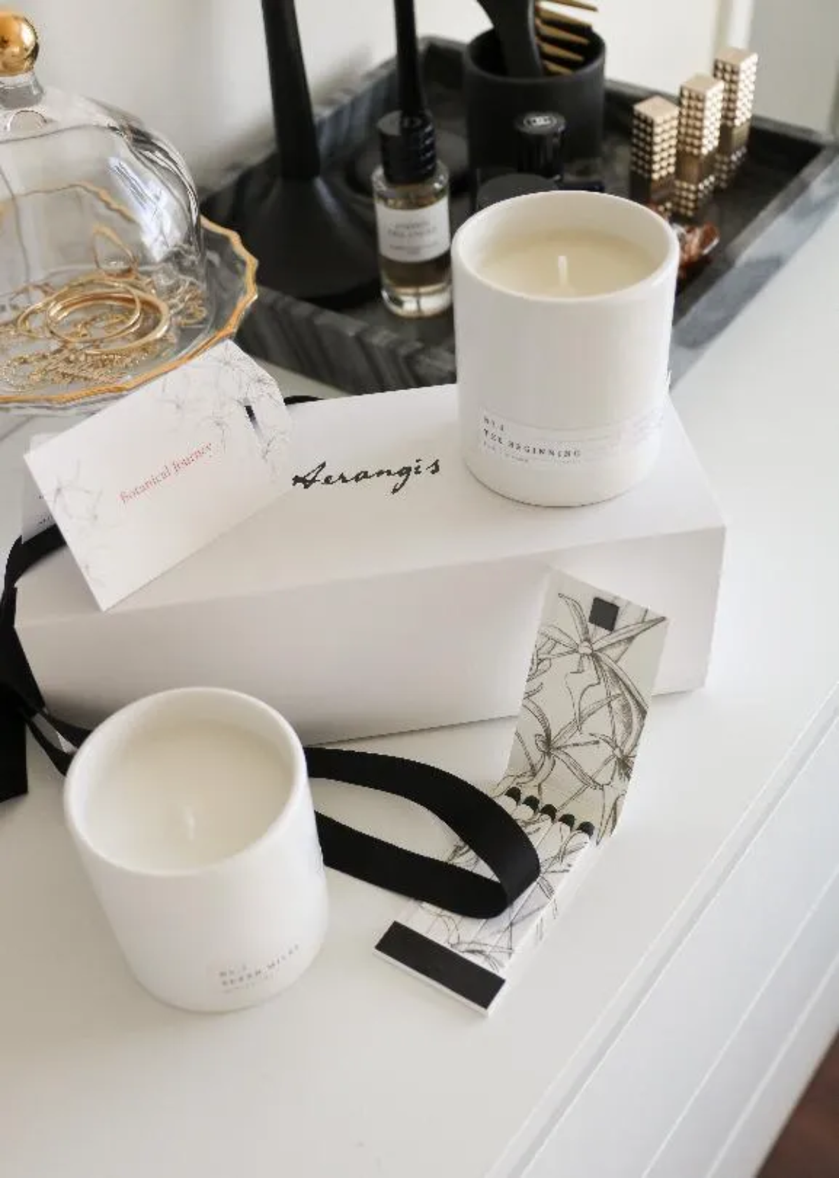 White ‘The Beginning’ candle with gift box, ribbon, and note card styled on a vanity tray
