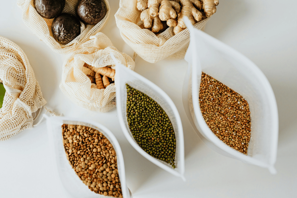 Reusable mesh bags holding lentils, mung beans, ginger and turmeric pieces.