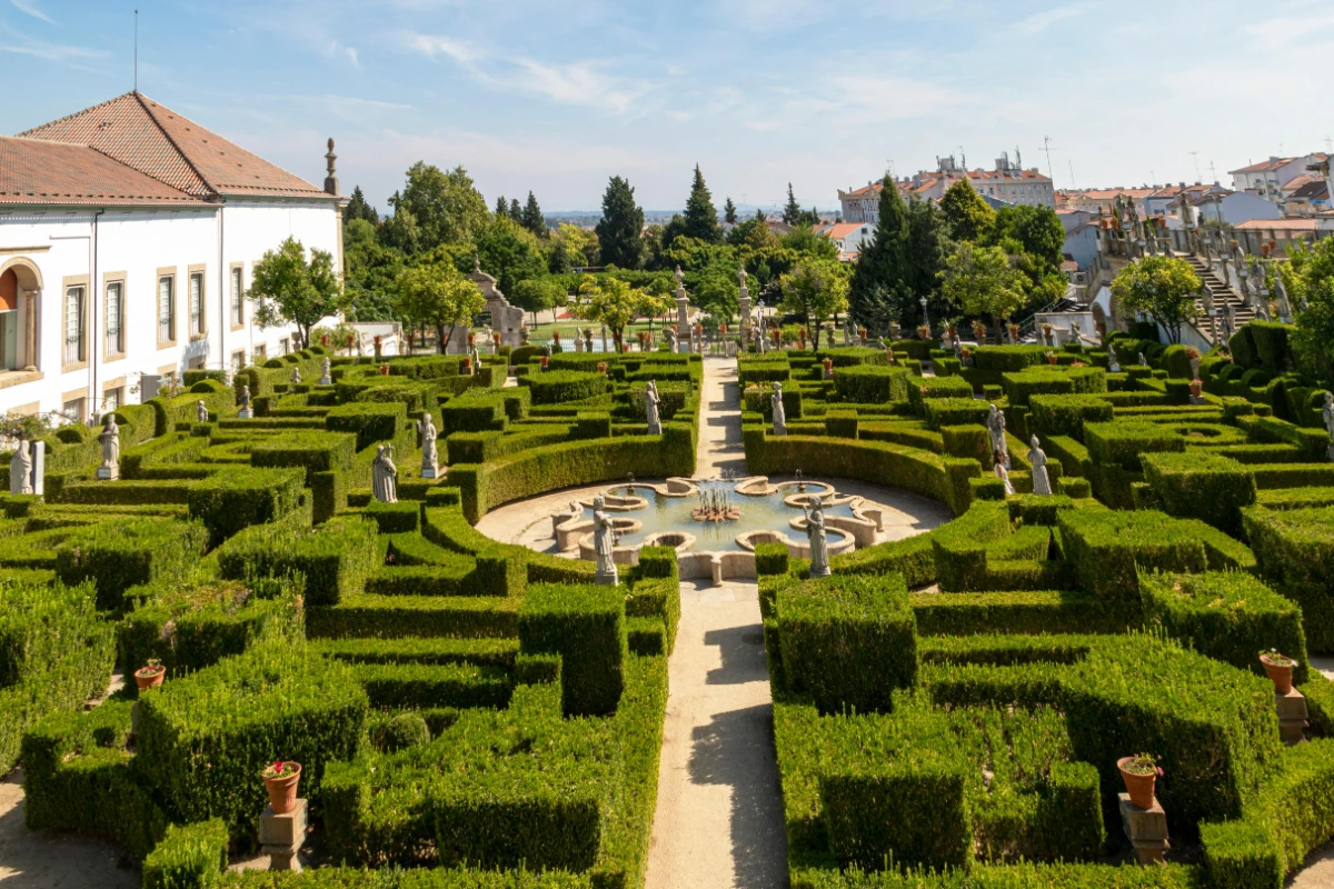Historic garden maze in Castelo Branco, Portugal with central fountain, statues, and symmetrical hedge design.