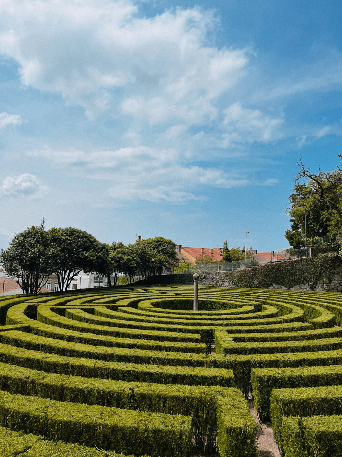 Circular hedge labyrinth centered by stone column.