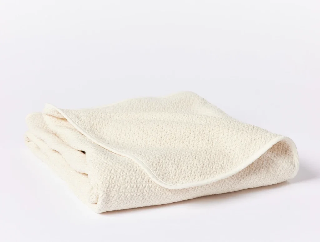 Coyuchi organic cotton throw blanket in soft cream with textured weave and minimal finish