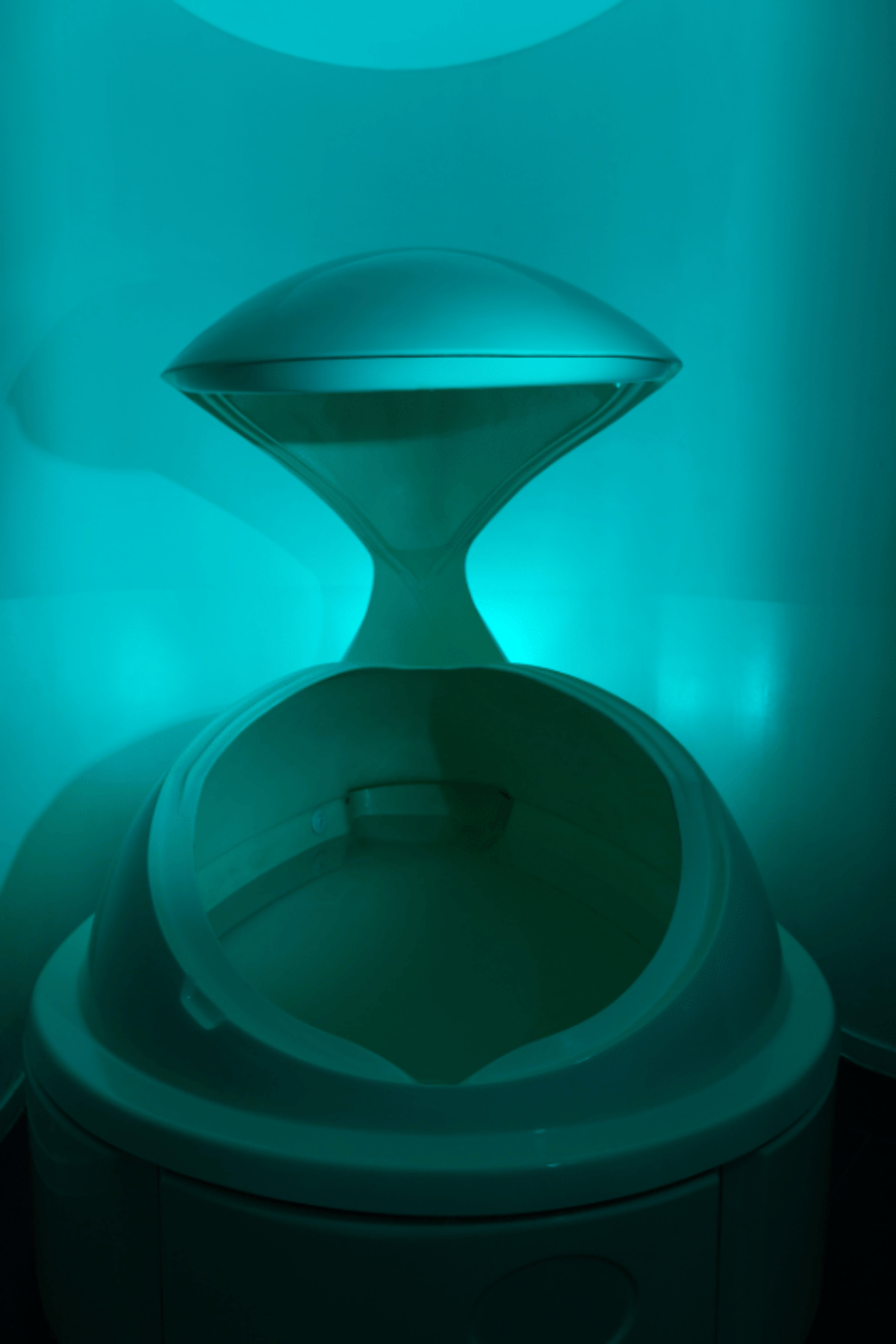 Teal-lit enclosed float pod with hinged dome open.