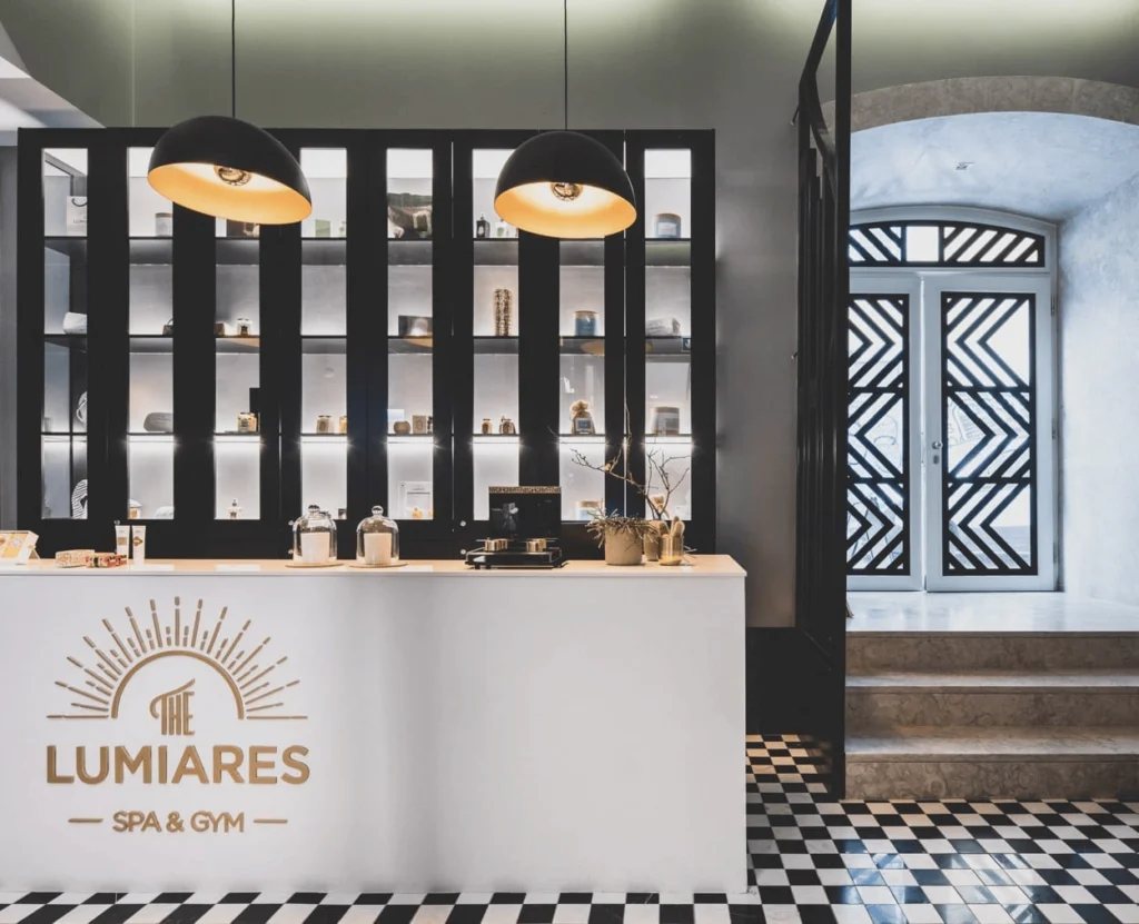 The Lumiares Spa reception in Lisbon, black display wall, white counter with gold logo and checkerboard marble floor
