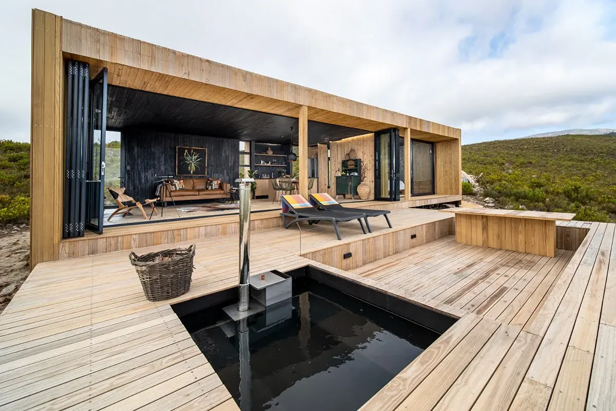 Contemporary Mount Grey eco cabin featuring wrap-around timber deck, wood-fired plunge pool and panoramic fynbos mountain views.