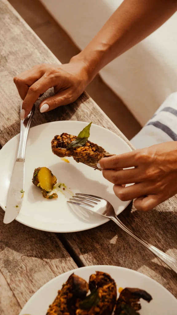 Hands holding a plated dish during an outdoor dining moment on a wooden table