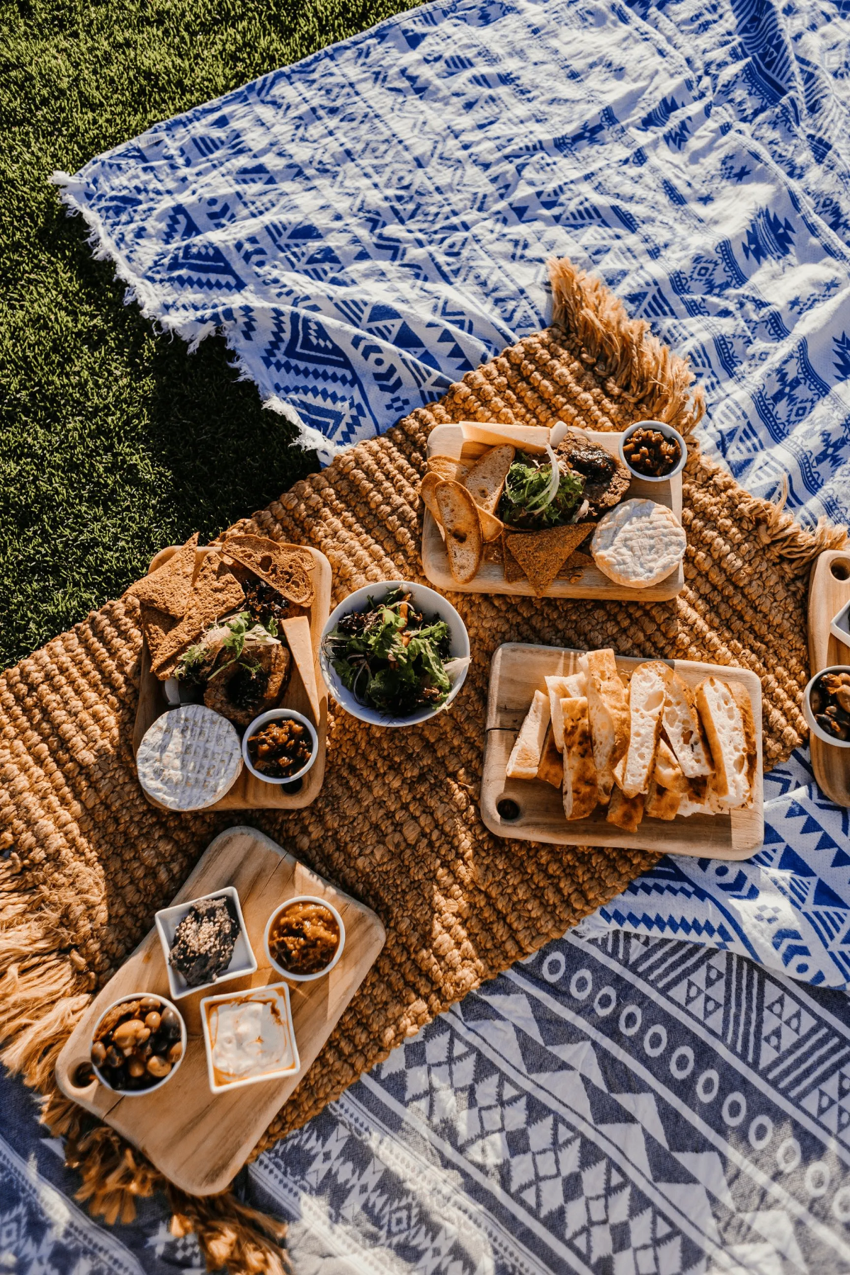 Picnic blankets laid with boards of bread, cheese, salads and small dip bowls.