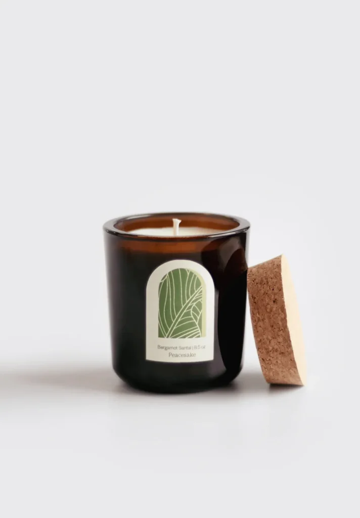 Peacesake Bergamot Santal 8.5 oz soy candle in amber jar with cork lid and botanical label, bergamot-sandalwood aroma