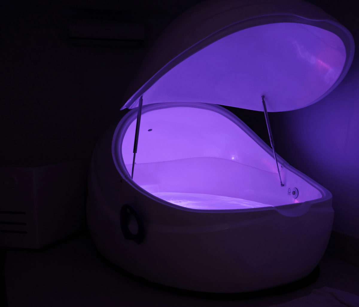 White sensory-deprivation tank glowing purple with lid.