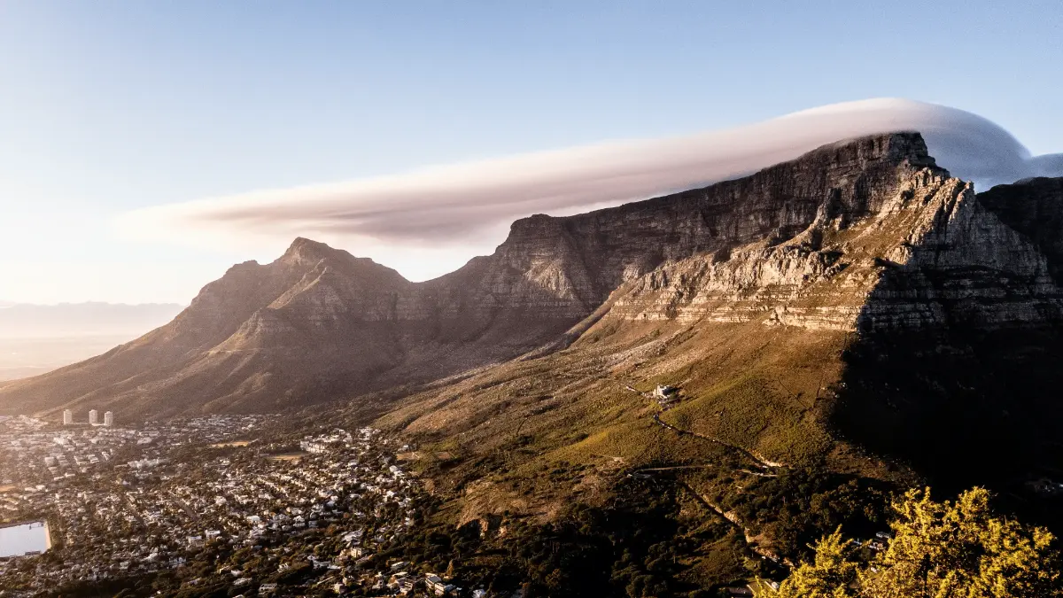 Signature “table-cloth” cloud drapes Table Mountain and Devil’s Peak as sunrise illuminates Cape Town below.
