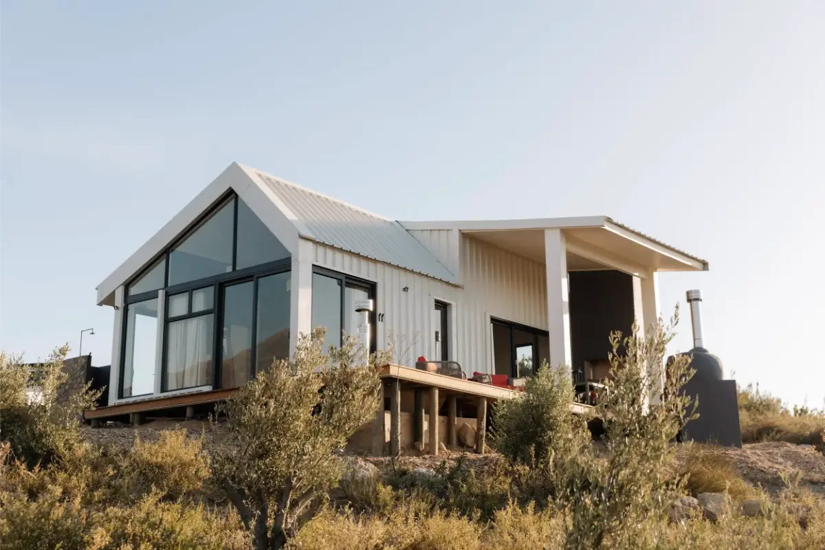 Modern white-clad Untether cabin perched above the Breede River Valley.