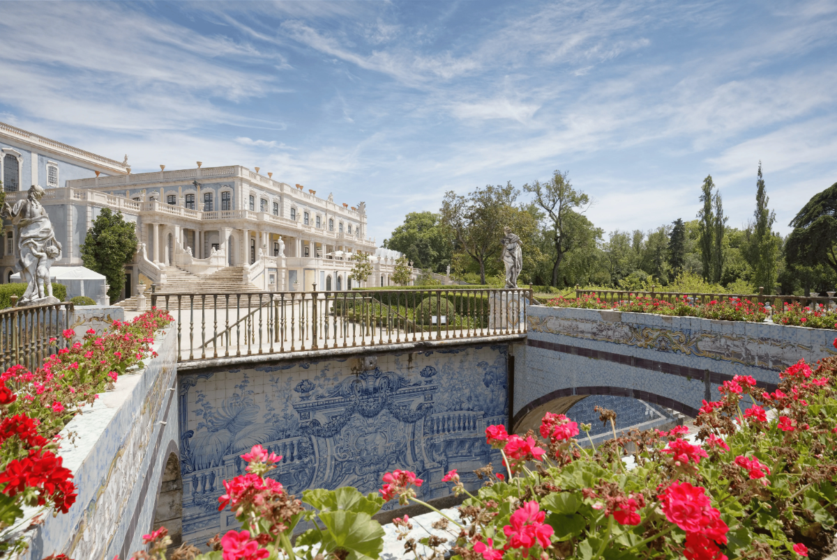 Ornate azulejo-lined canal and floral terraces beside the neoclassical wing of Queluz Palace.