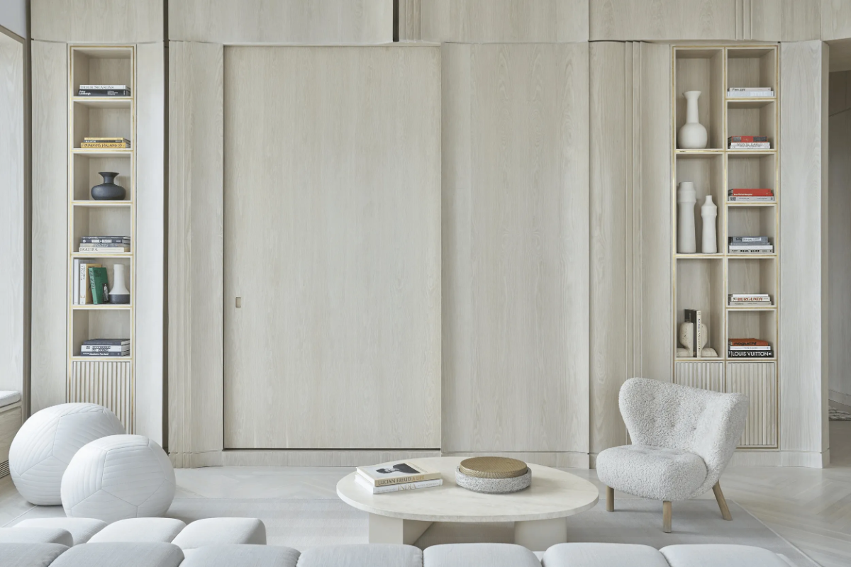 Sissy + Marley Park Ave living room with pale wood paneling, built-ins, boucle chair, modular sofa and round marble table.