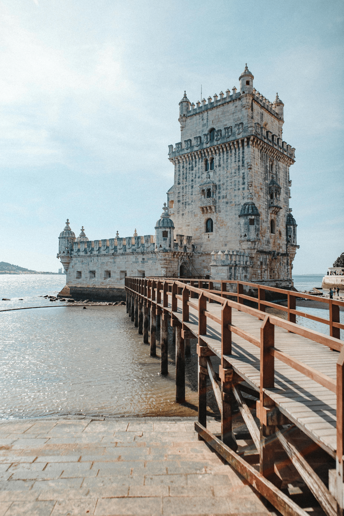 Daytime view of Belém Tower in Lisbon, Portugal, seen from the wooden footbridge over the Tagus River.