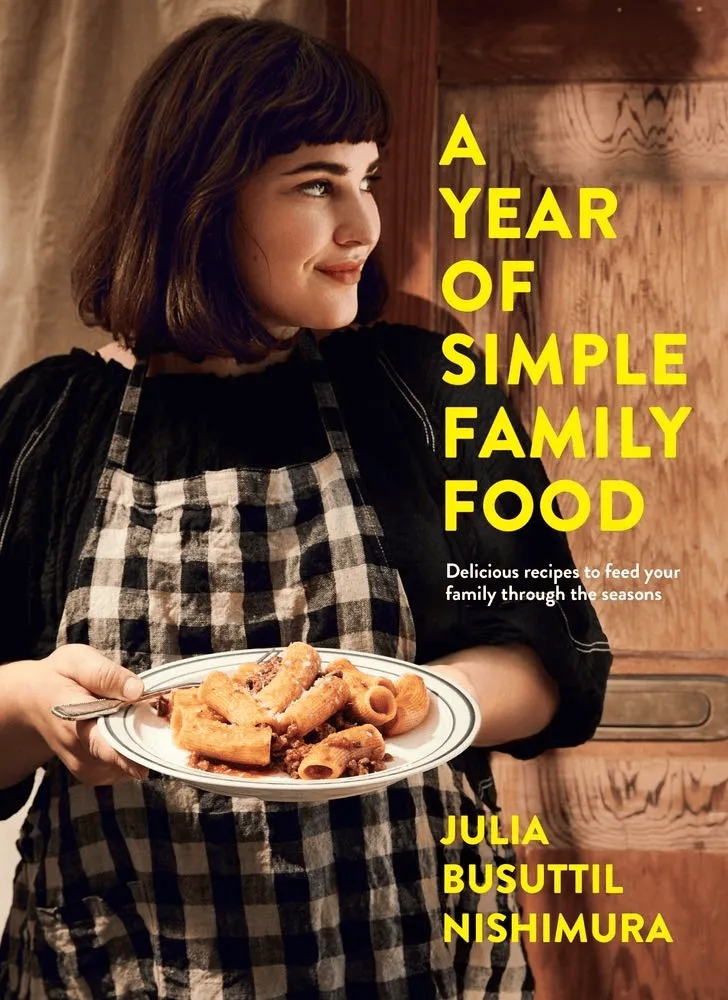 Cover of “A Year of Simple Family Food” by Julia Busuttil Nishimura with author serving hearty pasta dish in kitchen.