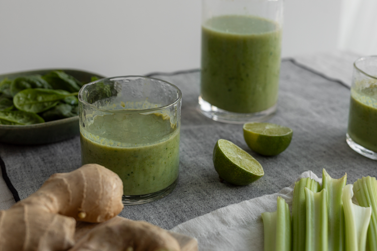Green smoothie in textured glasses on a grey linen table.