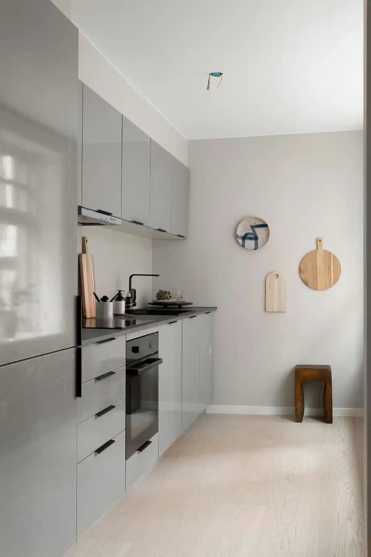 Slim grey galley kitchen with black hardware and black-top counters.