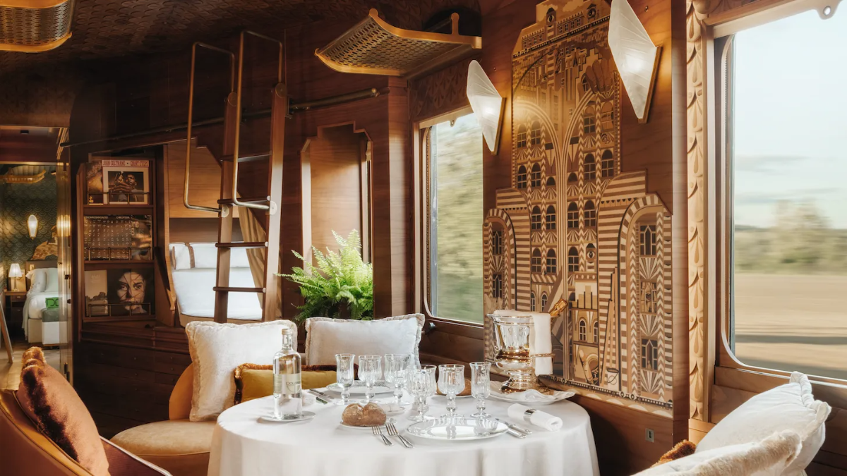Art-deco luxury Orient Express train suite, wood paneling and landscape rushing past the window.