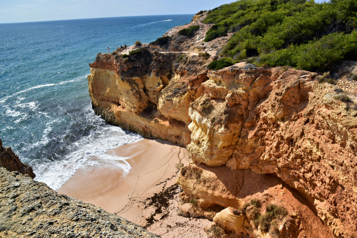 Secluded sandy cove under golden cliffs at Praia da Marinha, Atlantic surf gently lapping the shore.