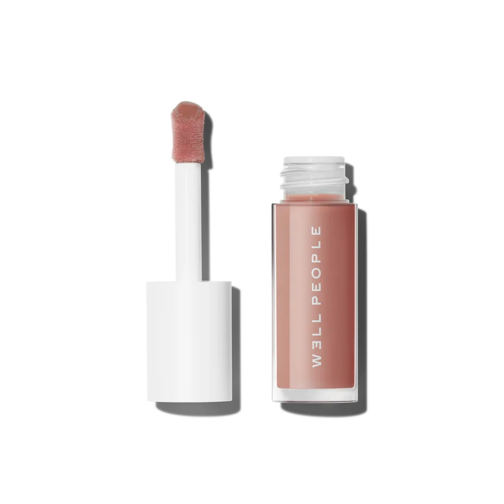 Well People Lush Lip Tinted Lip Oil in soft nude; open tube with doe-foot applicator shown next to clear bottle.