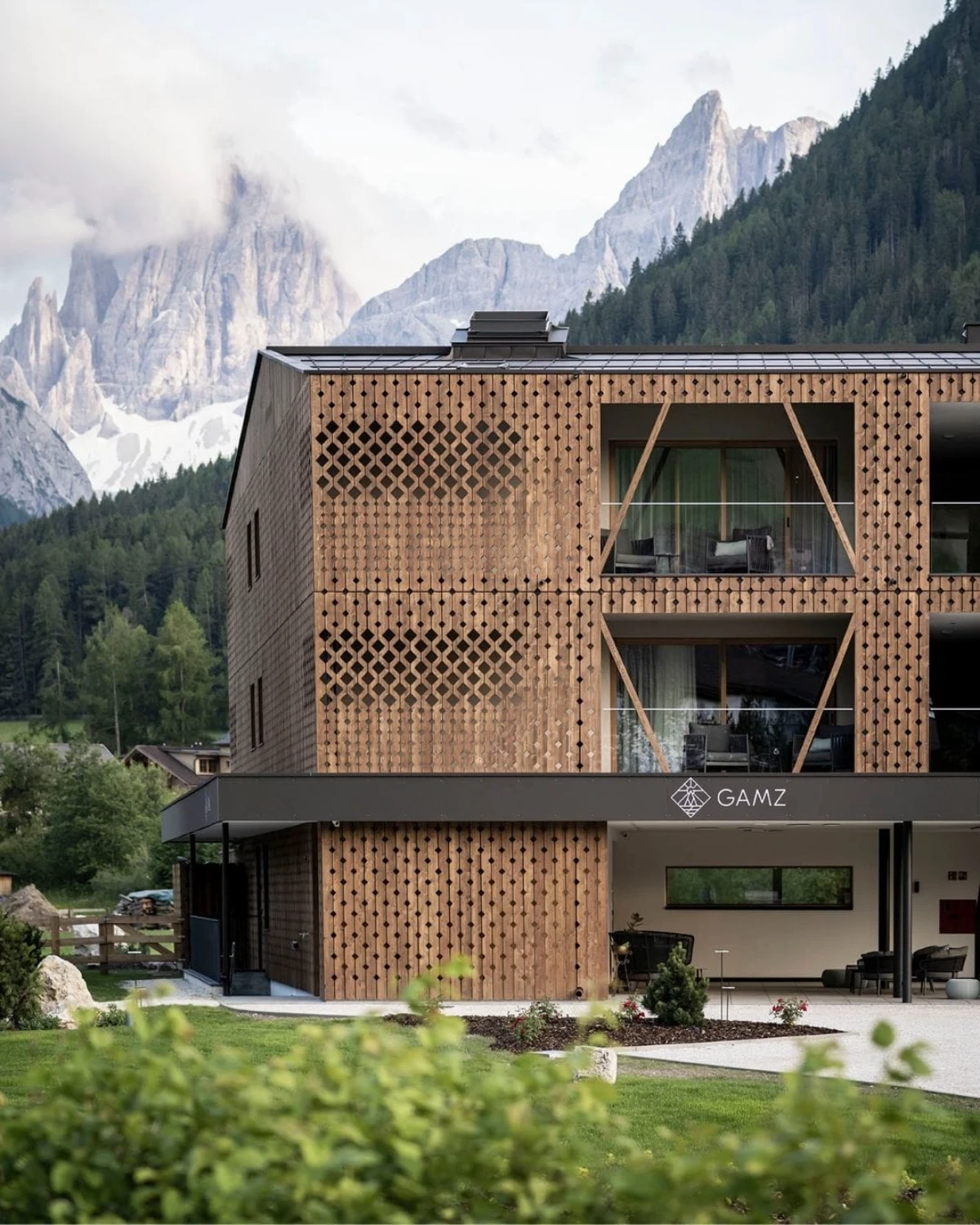 Aparthotel Gamz in Sesto with modern wood facade set against dramatic Dolomite peaks.