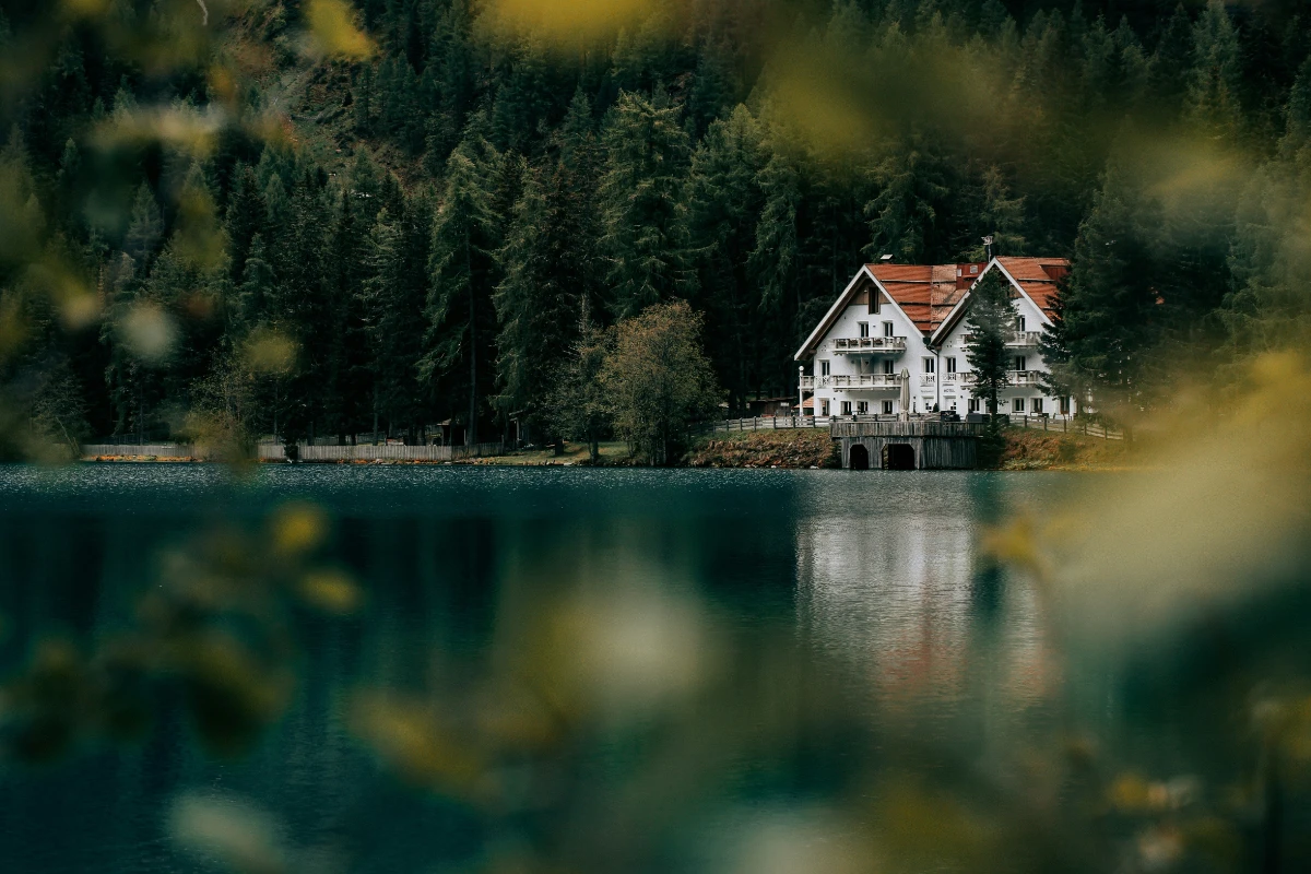 Framed view of Lago di Braies with forest and lakeside hotel through soft foreground.