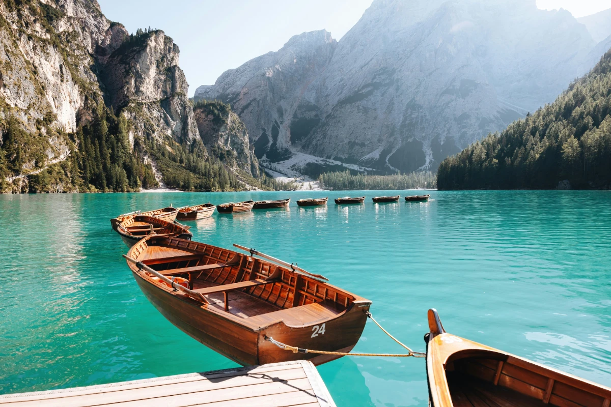 Wooden rowboats on Lago di Braies with turquoise water and mountain backdrop.