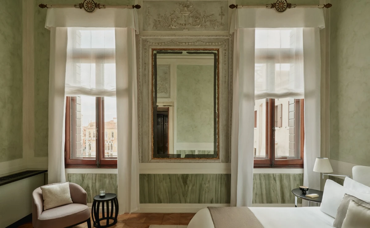 Light-filled bedroom at Aman Venice with tall windows, soft drapery, and classical detailing