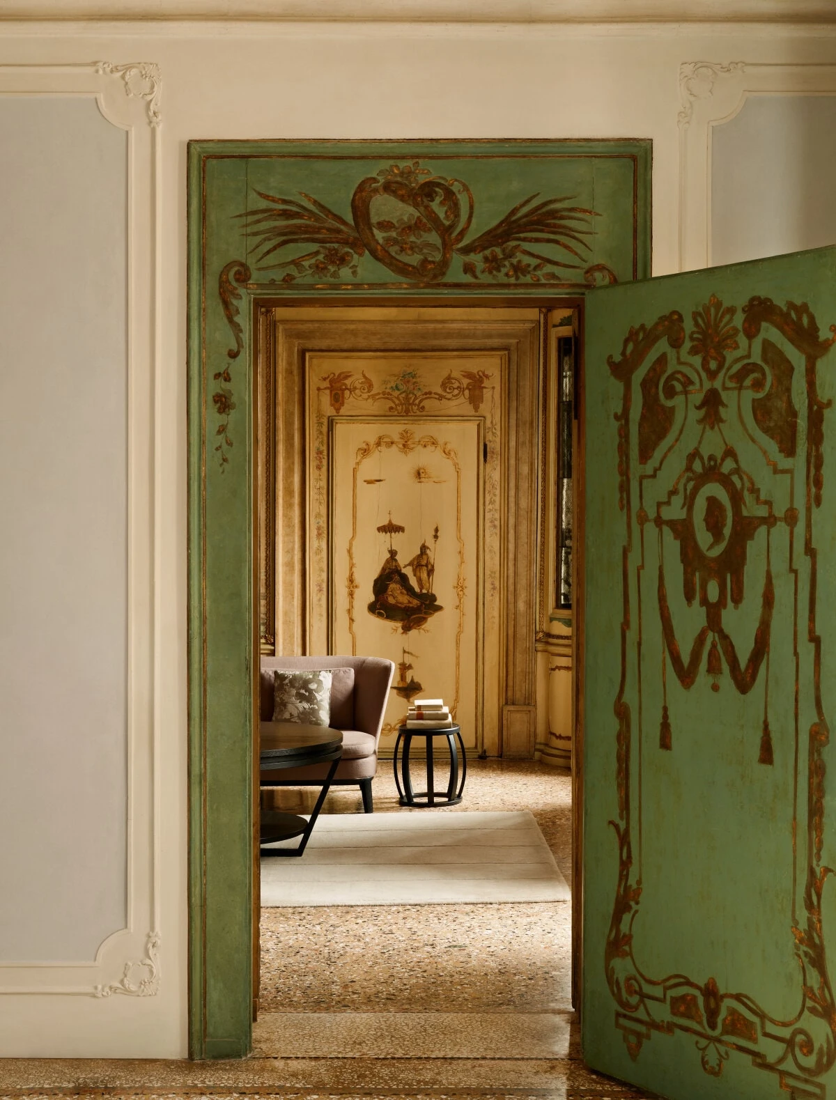 Ornate painted doorway inside Aman Venice with antique furnishings and frescoed interiors