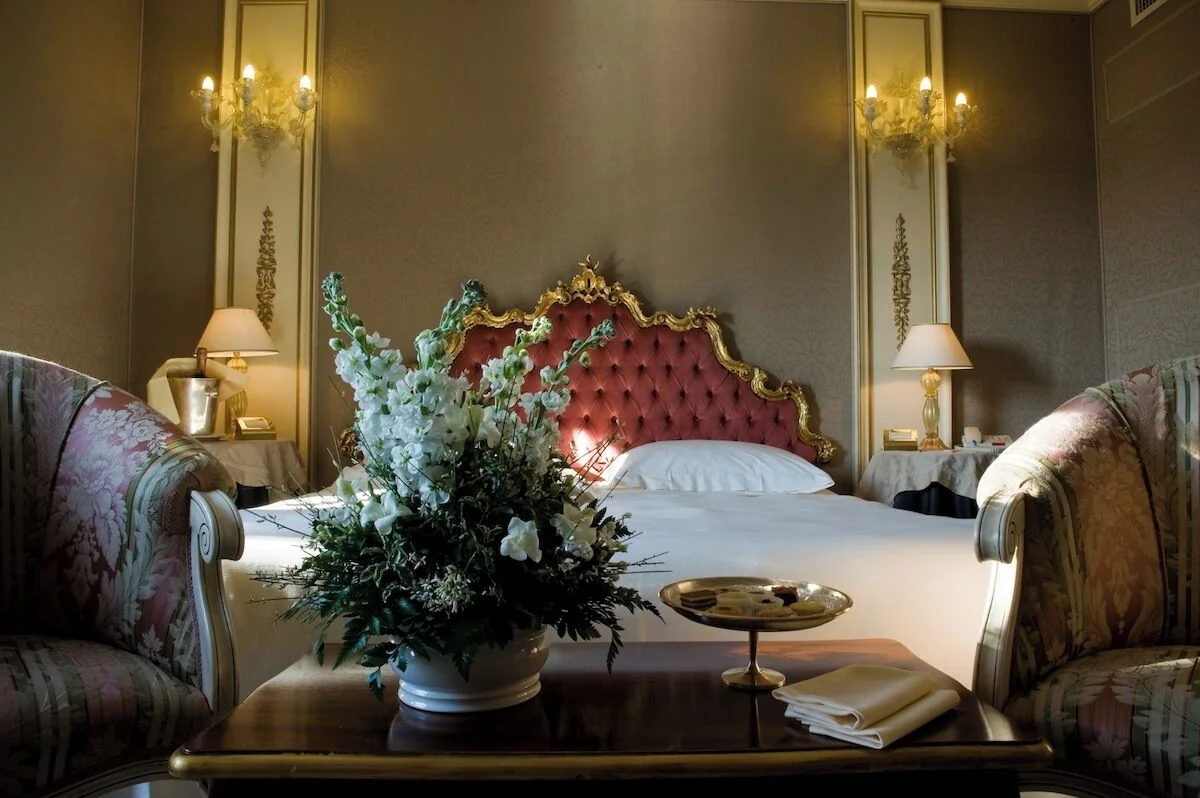 Classic suite at Ca Sagredo Venice with gilded headboard, floral furnishings, and soft lighting