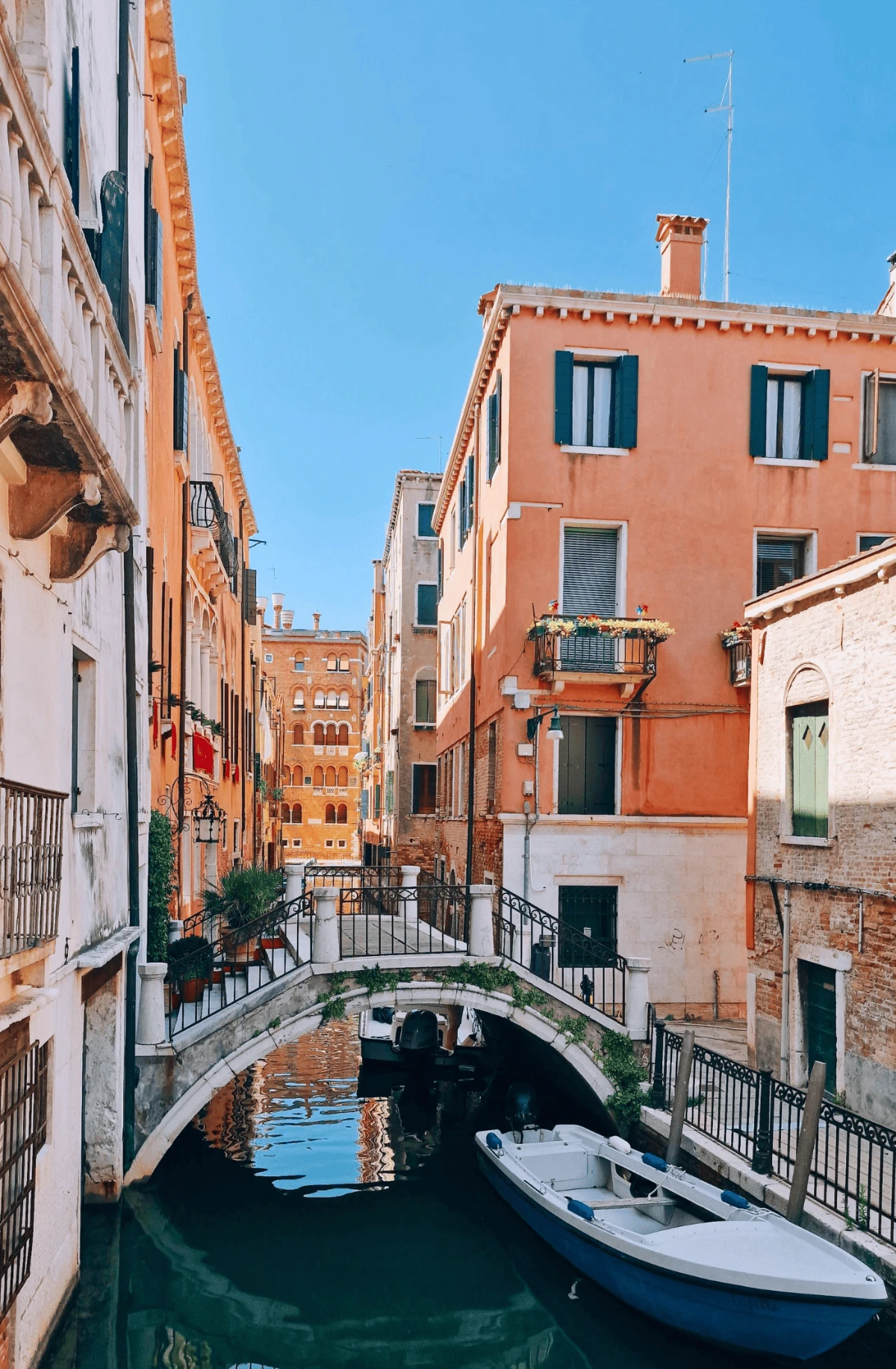 Quiet canal bridge in Cannaregio Venice lined with pastel buildings and moored boats