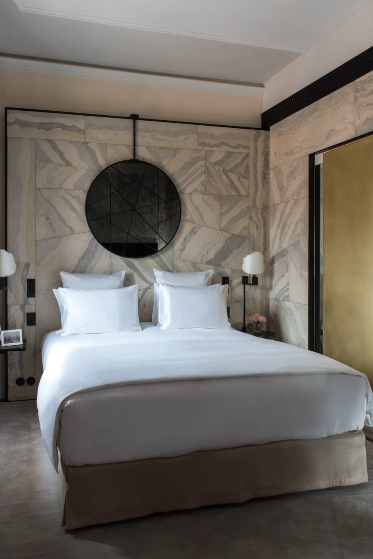 Minimal marble-lined suite at Nolinski Venice with sculptural wall detailing and white bedding