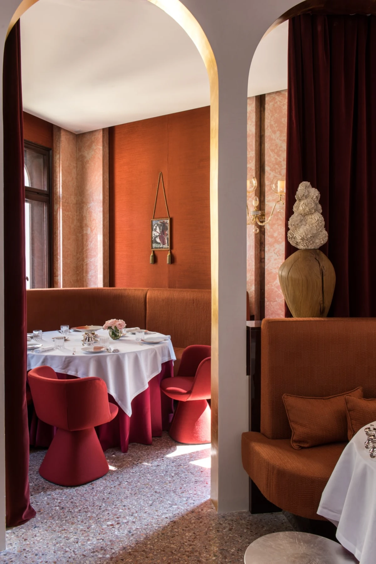 Warm-toned restaurant dining room at Nolinski Venice with velvet seating and arched interiors
