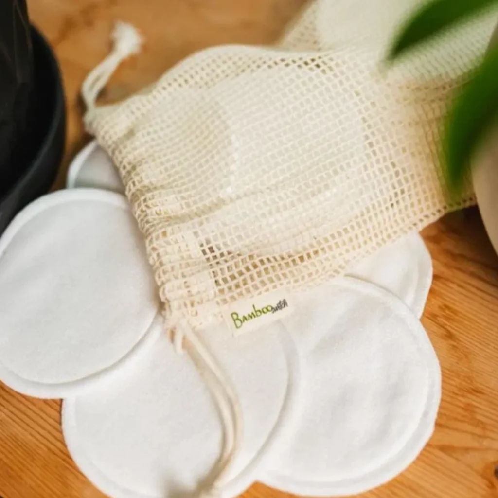 Bamboo Switch reusable rounds fanned beneath a branded mesh laundry bag on a warm timber surface.