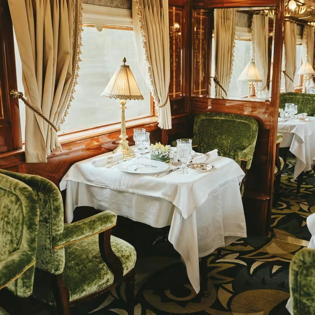 A table for two dressed in white linen in the Étoile du Nord restaurant, with green velvet chairs.