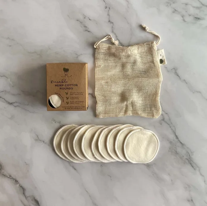 Mother Earth reusable hemp cotton rounds laid out beside kraft box packaging and a mesh laundry bag.