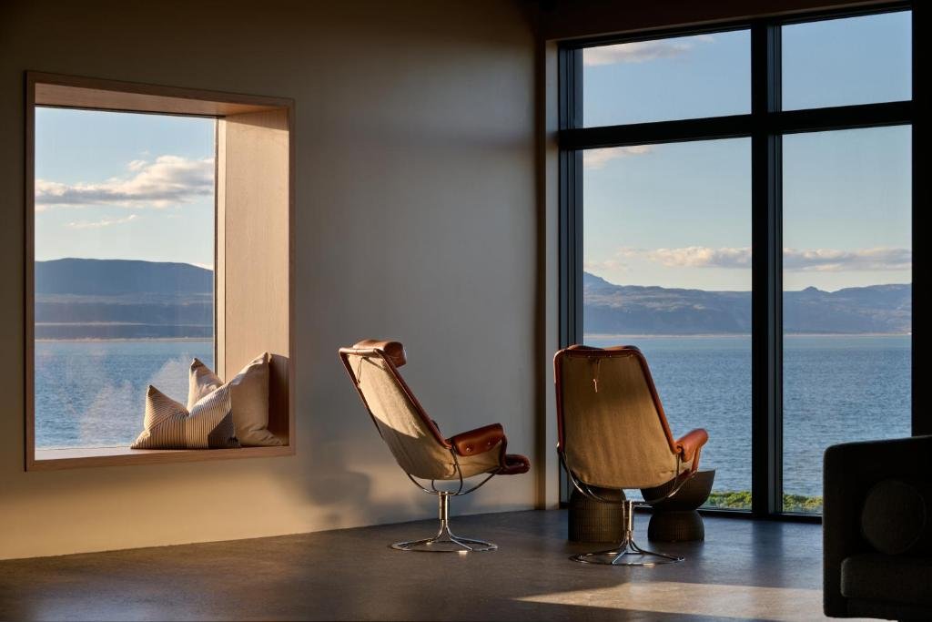 Two leather-trimmed lounge chairs and a deep window seat at Black Sand Hotel, facing the water at golden hour.