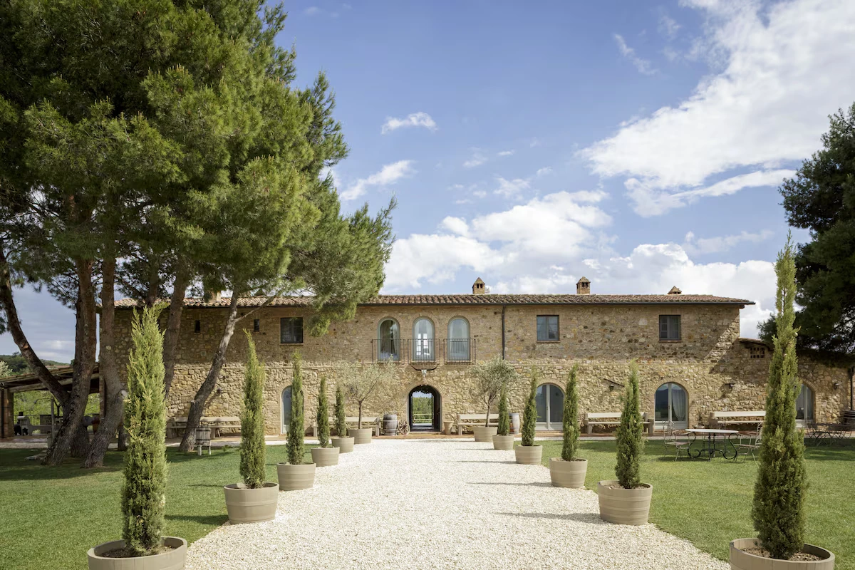 Conti di San Bonifacio, a restored stone farmhouse at the end of a gravel walk lined with potted cypress trees.