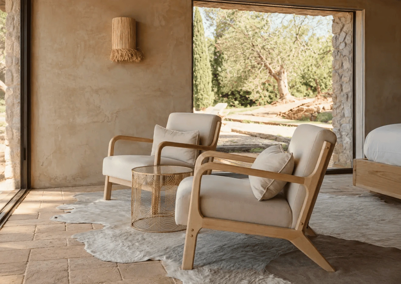 Linen armchairs on a sheepskin rug at Conti di San Bonifacio, facing a garden view of an ancient olive tree.