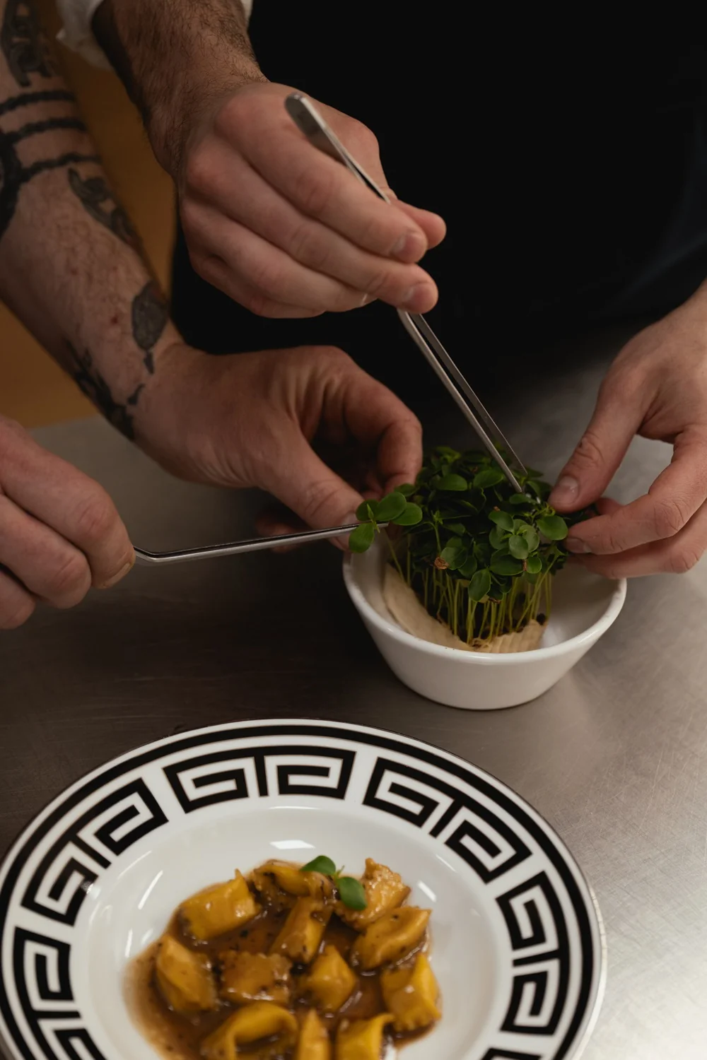 Microgreens are arranged beside filled pasta on a Greek key plate during a cooking class at Limonaia Casa Ruffino.